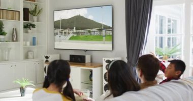 Mutlu bir ailenin evde oturup TV 'de yüksek atlama müsabakalarını izlemesinin birleşimi. spor, rekabet, eğlence ve teknoloji konsepti dijital olarak oluşturulmuş video.