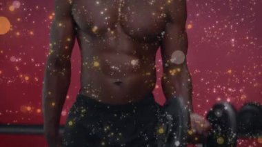 Güçlü kaslı bir adamın dambıllarını kaldırırken ışıldayan beneklerin canlandırılması. Spor ve spor konsepti dijital olarak oluşturulmuş video.