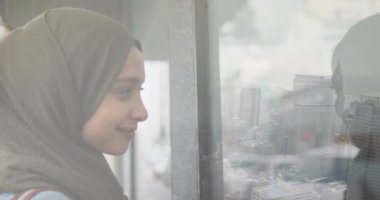 Şehre bakan tesettürlü gülümseyen Asyalı kadın animasyonu. Dijital ortamda üretilen bir video..