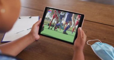Masada maske takmış, tablette hokey maçı izleyen bir kadın. covid 19 konseptinde dijital olarak üretilen spor, rekabet, eğlence ve teknoloji.