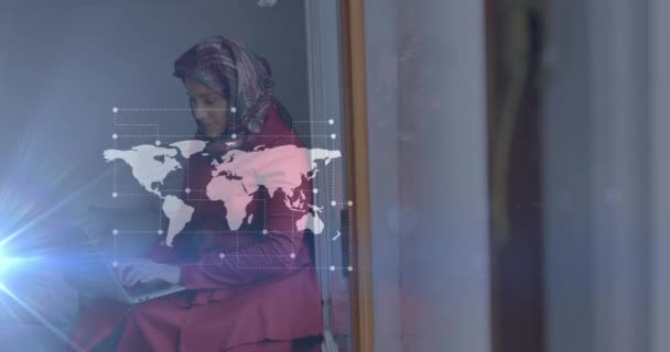 在亚洲女人头上用头巾 坐着和使用笔记本电脑绘制世界地图的动画 数字视频通信技术 — 图库视频影像