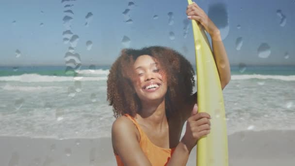 Animering Vattendroppar Över Leende Afrikansk Amerikansk Kvinna Stranden Med Surfbräda — Stockvideo
