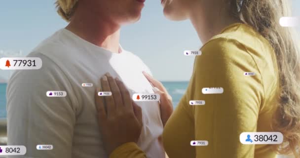 海辺を受け入れる愛の白人カップルの上にバナー上のソーシャルメディアアイコンのアニメーション ソーシャルメディア デジタルインターフェース 接続概念デジタル生成ビデオ — ストック動画