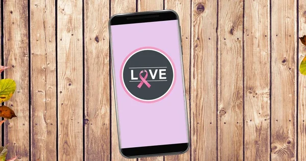 Composition of pink ribbon logo and love text on the smartphone screen. breast cancer positive awareness campaign concept digitally generated image.