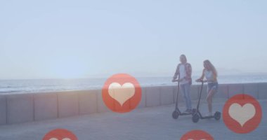 Sosyal medya kırmızı kalp ikonlarının deniz kenarında elektrikli scooter kullanan çiftler üzerinde canlandırılması. Sosyal medya, iletişim ve bağlantı konsepti dijital olarak oluşturulmuş video.