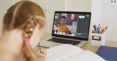 Evde online ders için dizüstü bilgisayar kullanan liseli kız, ekranda elini kaldıran erkek ve internet sohbeti yapıyor. iletişim teknolojisi ve çevrimiçi ilköğretim konsepti, dijital kompozit video.