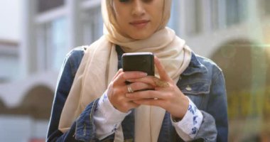 Kentin üzerinde akıllı telefon kullanan tesettürlü Asyalı kadın animasyonu. iletişim teknolojisi ve iletişimi sürdürmek, dijital olarak oluşturulmuş video.