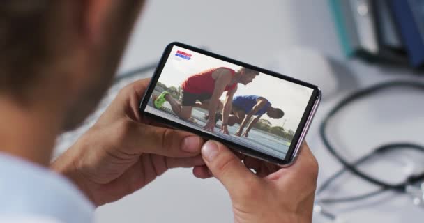 Atletizm Koşusunu Akıllı Telefondan Izleyen Erkek Doktorun Birleşimi Spor Rekabet — Stok video