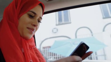 Şehrin her yerinde akıllı telefonlu tesettürlü gülen Asyalı kadın animasyonu. iletişim teknolojisi ve iletişimi sürdürmek, dijital olarak oluşturulmuş video.