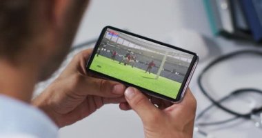 Erkek doktorun akıllı telefondan ragbi maçı izlemesinin birleşimi. spor, rekabet, eğlence ve teknoloji konsepti dijital olarak oluşturulmuş video.