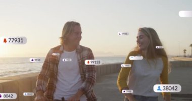 Gülümseyen beyaz bir çiftin deniz kenarında scooter sürmesi üzerine afişlerde sosyal medya simgelerinin canlandırılması. Sosyal medya, dijital arayüz ve bağlantılar konsepti dijital olarak oluşturulmuş video.