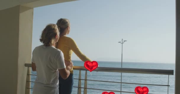 在海滨的阳台上 社交媒体红心气球的动画在情侣之间飞舞 社交媒体 通信和连接概念数字化生成的视频 — 图库视频影像