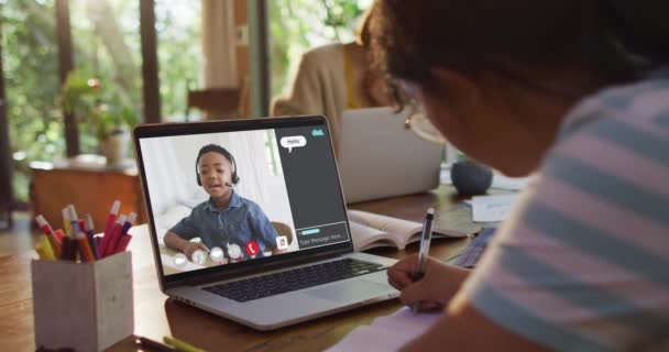 家庭でのオンラインレッスンのためのラップトップを使用して女子高生 画面上で男の子の話やWebチャットと 通信技術とオンライン初等教育の概念デジタル複合ビデオ — ストック動画