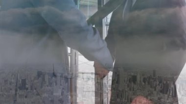 Şehir manzarası üzerinde el sıkışan iş adamlarının animasyonu. küresel iş, başarı ve iletişim konsepti dijital olarak oluşturulmuş video.