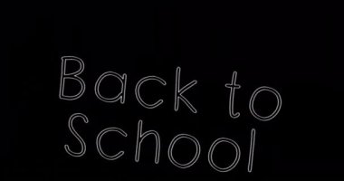 Siyah arkaplan üzerine okula dönüş metninin animasyonu. okul, eğitim ve öğrenim konsepti dijital olarak oluşturulmuş video.