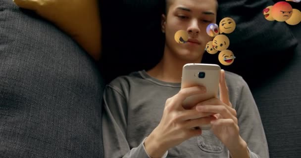 Multiple Face Emojis Floating Caucasian Man Using Smartphone Lying Couch — Stock Video