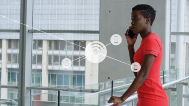 Ofiste akıllı telefondan konuşan Afrikalı Amerikalı iş kadınına karşı dijital ikonlar ağı. küresel ağ ve iş teknolojisi kavramı