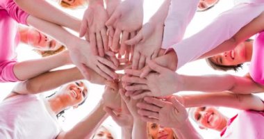 Güneşin altında el ele tutuşan bir grup gülümseyen kadın. Göğüs kanseri pozitif farkındalık kampanyası konsepti dijital olarak üretildi.