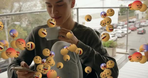 Múltiplos Emojis Rosto Flutuando Contra Homem Caucasiano Usando Smartphone Enquanto — Vídeo de Stock
