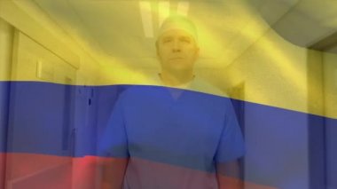Kolombiya bayrağı, hastanede cerrahi eldiven takan beyaz erkek sağlık görevlisine karşı dalgalanıyor. Sağlık ve Tıp Konsepti.