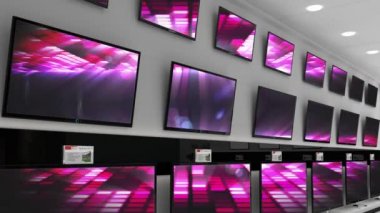 Elektronik mağazasının içinde senkronize video birden fazla televizyon ekranında oynuyor. elektronik ve perakende ticaret teknolojisi kavramı