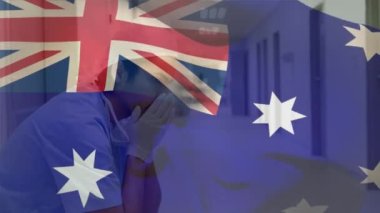 Hastanedeki Kafkasyalı erkek sağlık çalışanı üzerinde dalgalanan Avustralya bayrağının dijital bileşimi. Sağlık ve Tıp Konsepti.