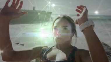Sahilde karın kası egzersizi yapan beyaz bir kadına karşı parlayan bir bağlantı ağı. Spor, spor ve teknoloji konsepti