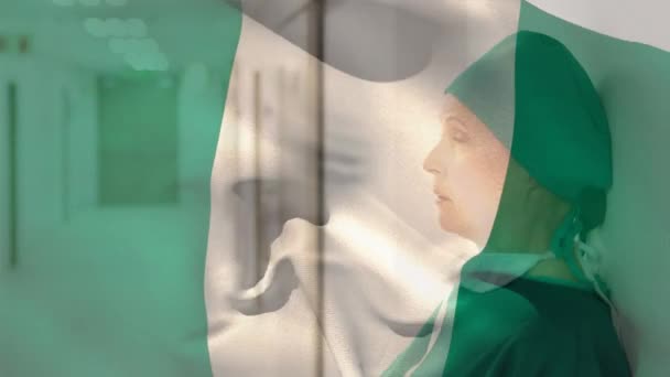 病院のストレスを受けた白人女性外科医に対して手を振るナイジェリアの国旗のデジタル構成 医療と医療の概念 — ストック動画