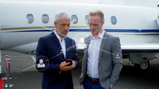 Sieć Ikon Profili Przeciwko Dwóm Białym Biznesmenom Korzystającym Smartfona Lotnisku — Wideo stockowe