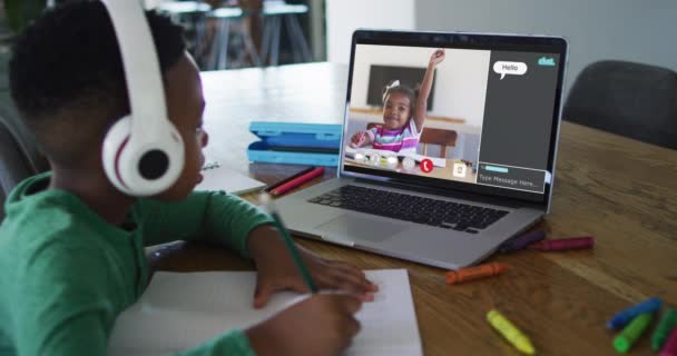 非洲裔美国男孩带着耳机做作业 同时在家里的笔记本电脑上有一个视频通话 远程学习和网上教育概念 — 图库视频影像
