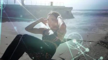 Sahilde karın kası egzersizi yapan beyaz bir kadına karşı parlayan bir bağlantı ağı. Spor, spor ve teknoloji konsepti