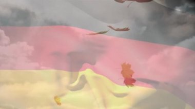 Sonbahar yaprakları üzerinde dalgalanan Alman bayrağının dijital bileşimi gökyüzündeki bulutlara doğru düşüyor. Sonbahar mevsimi konsepti