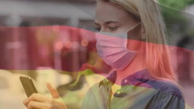 Belçika bayrağını sallayan beyaz kadın sokakta akıllı telefon kullanarak yüz maskesi takıyor. Coronavirus covid-19 salgın konsepti