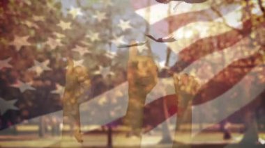 Amerikan bayrağı ve elleri sonbaharda parka doğru düşen yaprakları işaret ediyor. Sonbahar sezonu konsepti elleri başparmaklarını gösteriyor