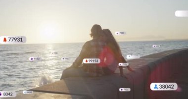 Kafkas çifti üzerinde artan sayılara sahip çoklu sayısal ikonlar deniz kenarında birlikte oturuyorlar. Sosyal medya ağı ve teknoloji kavramı