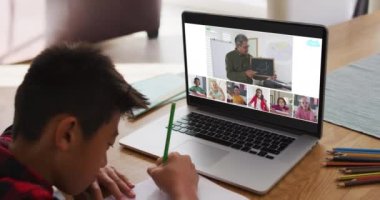 Asyalı çocuk ev ödevi yapıyor ve ev bilgisayarında öğretmen ve sınıf arkadaşlarıyla video konferansı yapıyor. uzak öğrenim ve çevrimiçi eğitim kavramı