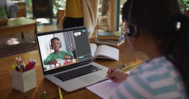 アフリカ系アメリカ人の女の子が宿題をして 自宅のノートパソコンで同級生とビデオ通話をしています 遠隔教育とオンライン教育の概念は — ストック動画