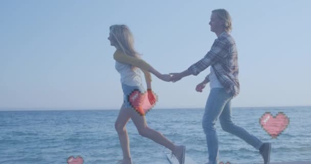 海の近くを歩いて手を握っている白人夫婦に対して浮かんでいる複数の赤いハートアイコン ソーシャルメディアネットワークとテクノロジーの概念 — ストック動画