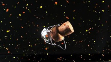 Şampanya mantarının üzerine konfeti düştü ve siyah arka plana konfeti düştü. Yeni yıl partisi ve kutlama konsepti