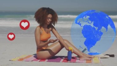 Sahilde güneş kremi süren Afrikalı Amerikalı bir kadının üzerinde yüzen dünya ve birden fazla kalp ikonu. Sosyal medya ağı ve teknoloji kavramı