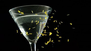 Kokteyl bardağının üzerine siyah arka plana düşen altın konfetilerin dijital bileşimi. gece hayatı ve bar partisi konsepti