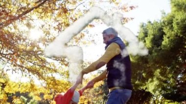 Dumanlar, parkta kızıyla oynayan beyaz bir babaya karşı bir ev şekli oluşturuyor. aile, sevgi ve birliktelik kavramı