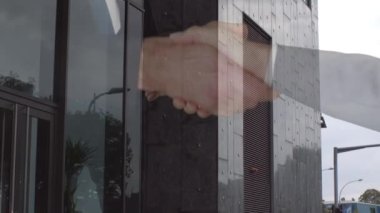 İşadamı ve iş kadınının arka plandaki yüksek binalara el sıkışması. iş ortaklığı ve teknoloji kavramı