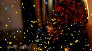 Konfeti bardağa dökülen şarabın üzerine düşüyor. Yeni yıl kutlaması ve gece hayatı konsepti