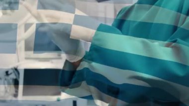 Yüz maskeli cerrahların üzerinde sallanan Yunan bayrağının animasyonu. küresel covid 19 salgın hastalık ve sağlık hizmetleri konsepti dijital olarak oluşturulmuş video.