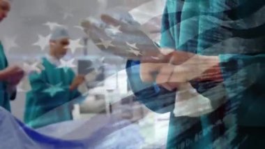 Maskeli cerrahların üzerinde sallanan Amerikan bayrağının animasyonu. küresel covid 19 salgın hastalık ve sağlık hizmetleri konsepti dijital olarak oluşturulmuş video.