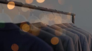 Giysi dükkanında asılı duran ceketlerin üzerinde bokeh ışıkları animasyonu. moda ve giyim sektörü ve perakende konsepti dijital olarak oluşturulmuş video.