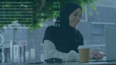 Laptop kullanan tesettürlü bir kadın hakkında finansal veri işleme animasyonu. küresel iş, finans, bağlantılar ve teknoloji konsepti dijital olarak oluşturulmuş video.