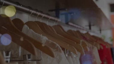 Dükkanda asılı duran kıyafetlerin üzerinde bokeh ışıkları animasyonu. moda ve giyim sektörü ve perakende konsepti dijital olarak oluşturulmuş video.