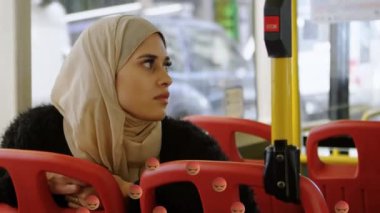 Otobüste akıllı telefon kullanan tesettürlü bir kadın için düşen emojilerin animasyonu. küresel sosyal medya, dijital arayüz, teknoloji ve bağlantılar konsepti dijital olarak oluşturulmuş video.